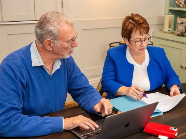 Linda and Andrew gent working side by side at a desk reviewing documents